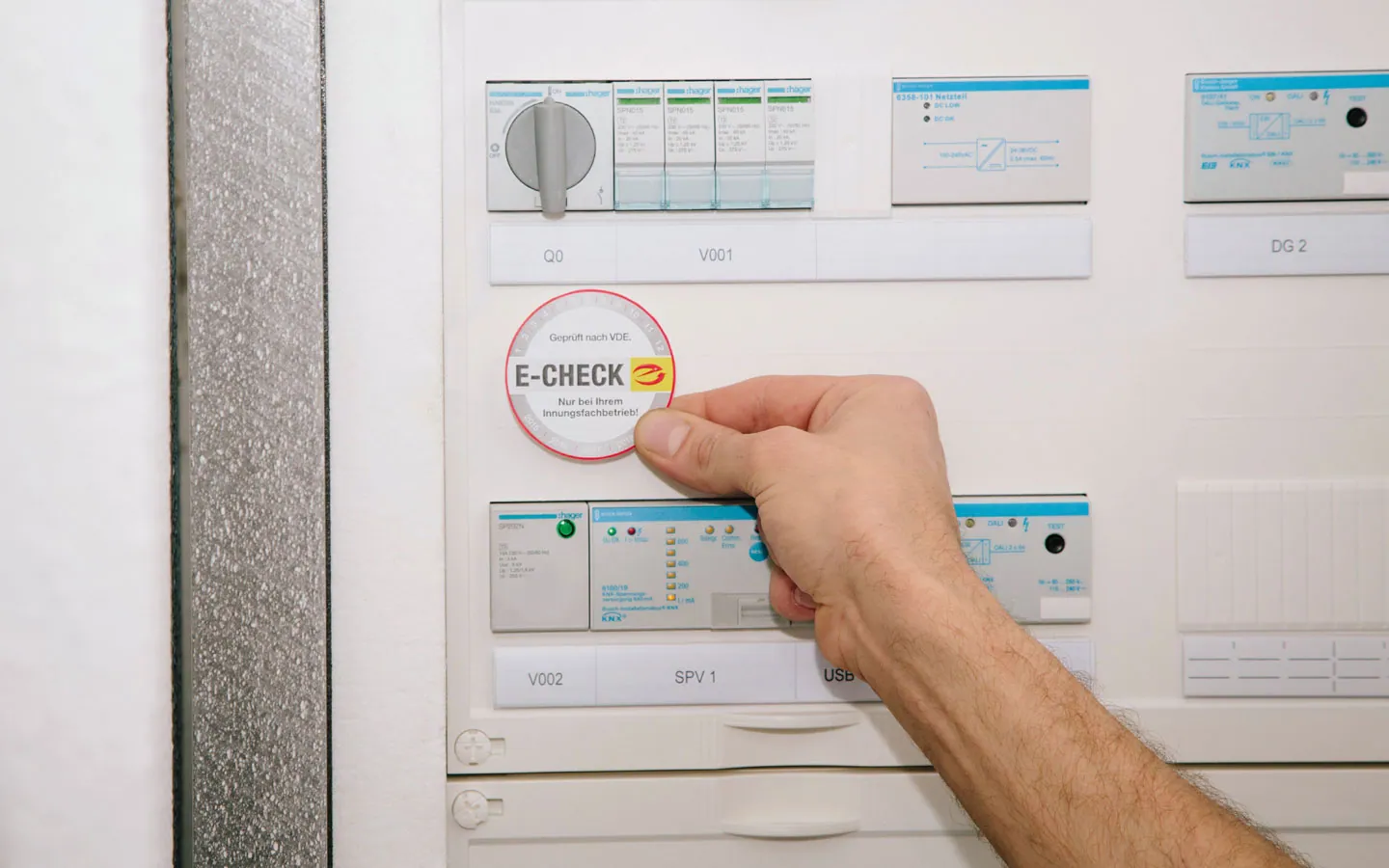 E-CHECK - Mitarbeiter klebt in der Verteilung die E-CHECK Plakette an &middot; B+B Mess- und Sicherheitstechnik